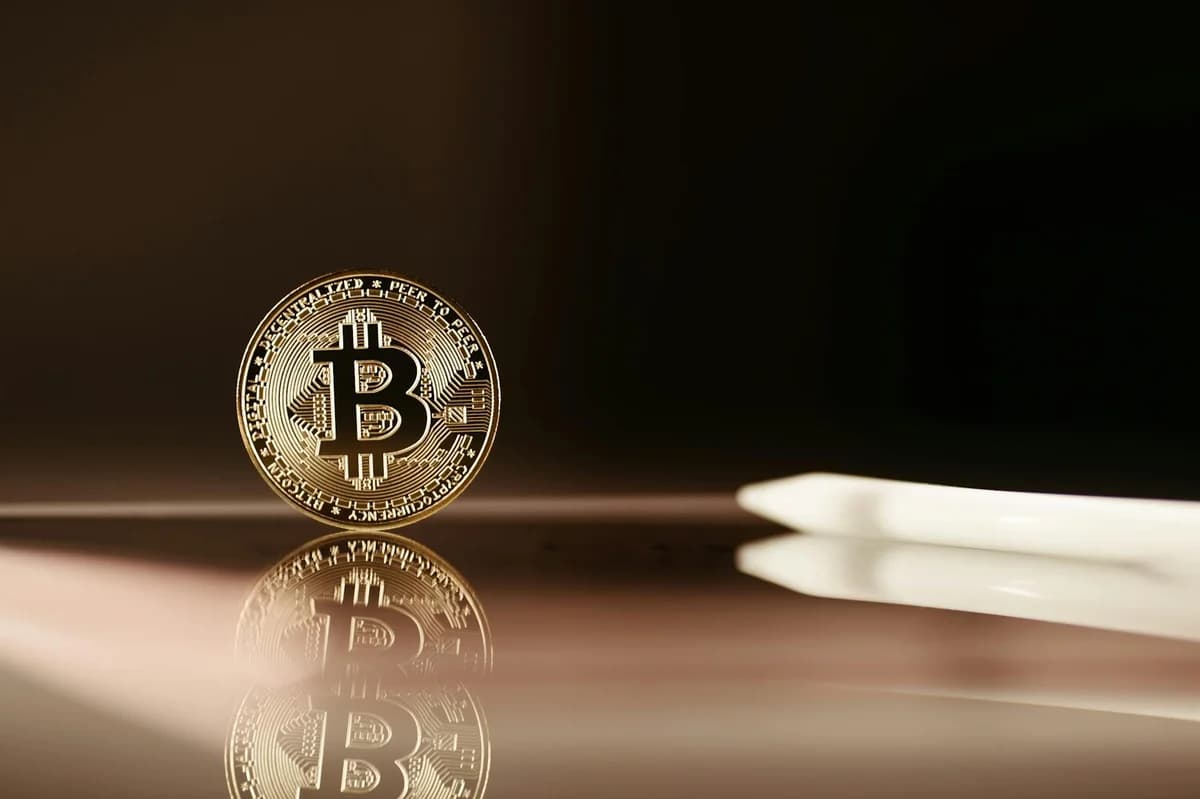 Close-up of a Bitcoin coin on a vivid orange background, symbolizing digital currency.