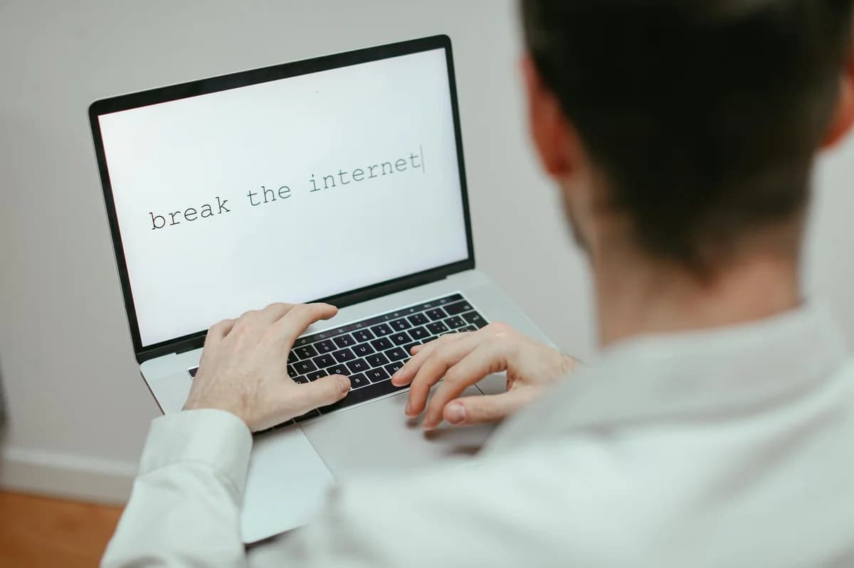 A person typing on a laptop showing the provocative message 'break the internet'.