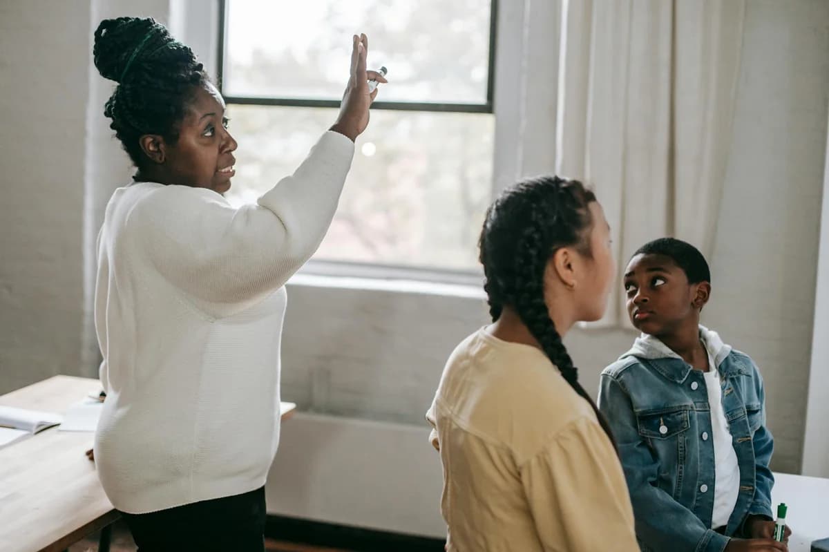 Clever African American woman explaining subject to attentive diverse pupils in modern classroom