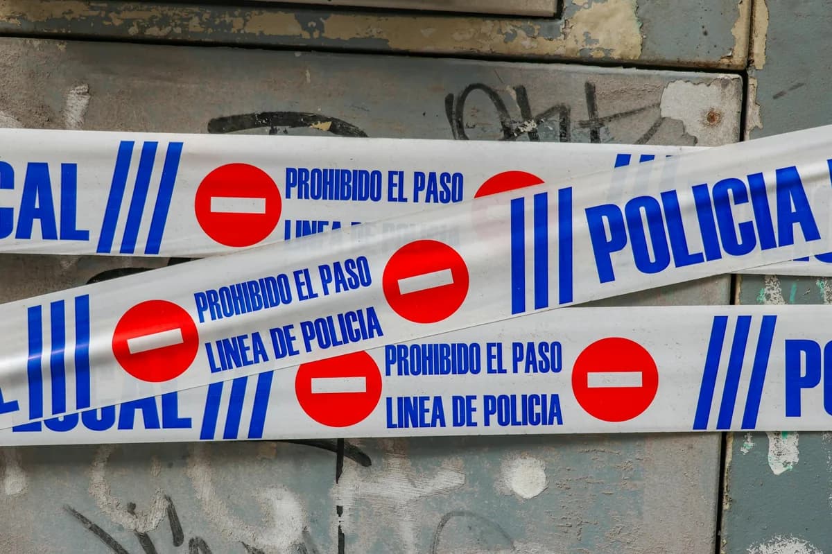 Police tape with 'Prohibido El Paso' against graffiti-covered wall. Crime scene concept.