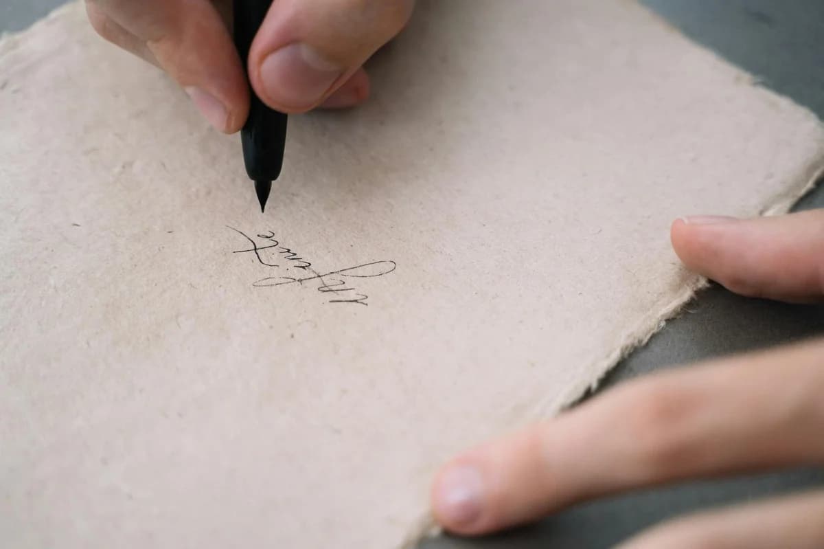 Macro shot of a pen writing a signature on white paper, emphasizing precision.