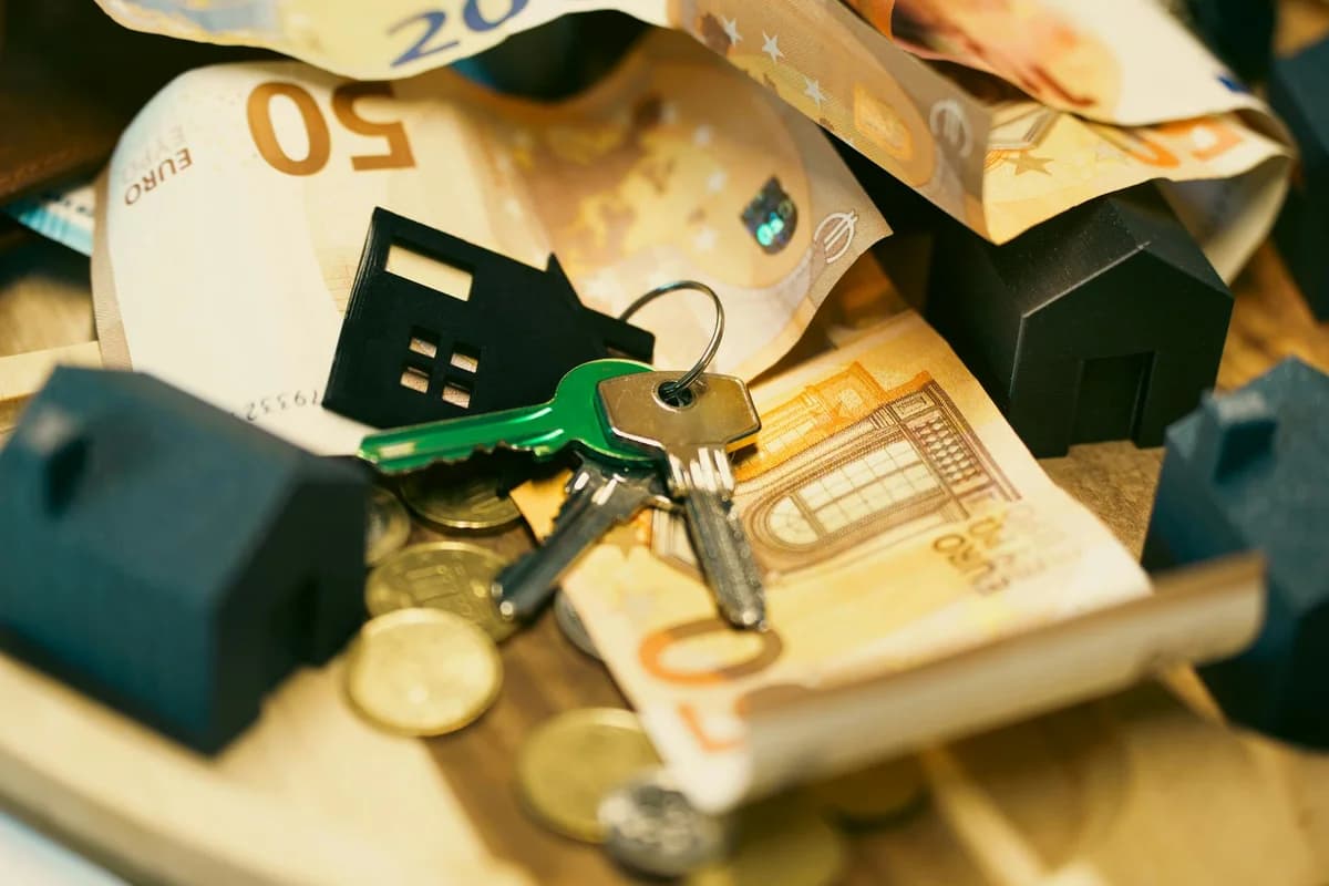 Miniature houses, euro bills, and a house key symbolize real estate investment and property transactions.
