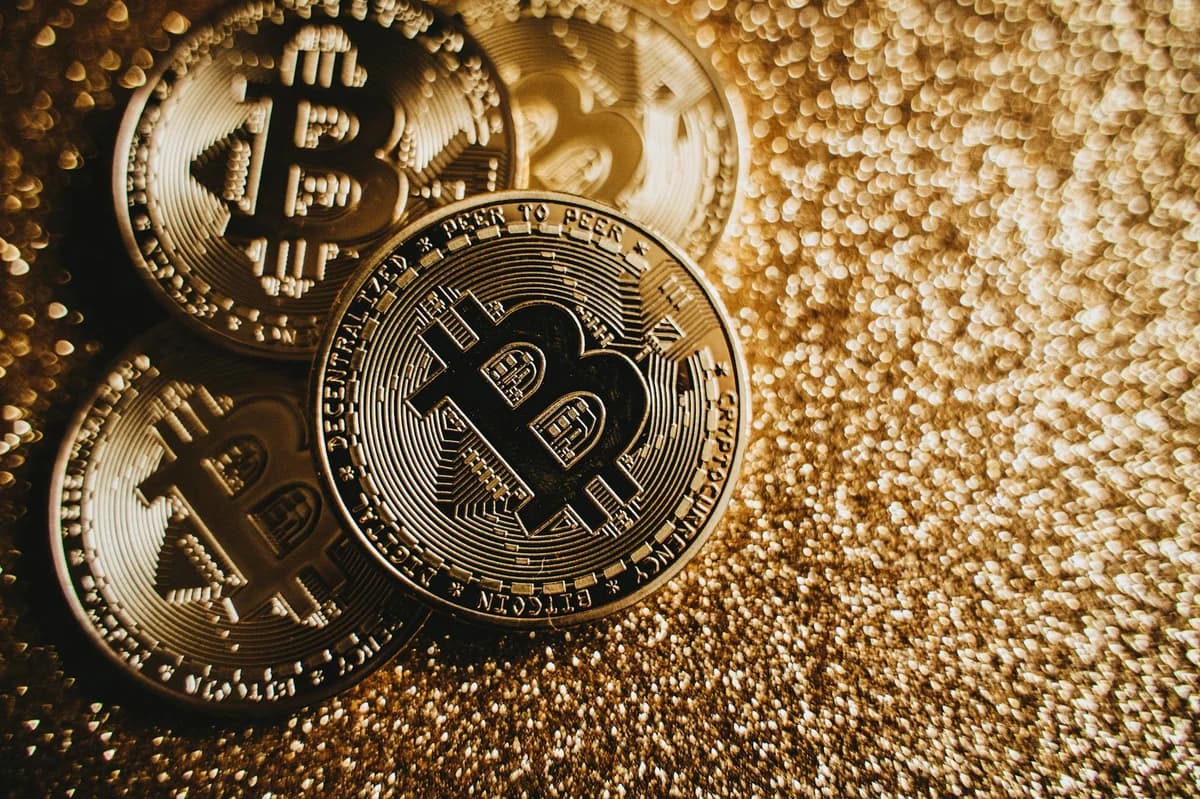 Gold-colored bitcoins arranged diagonally on a dark wooden surface.