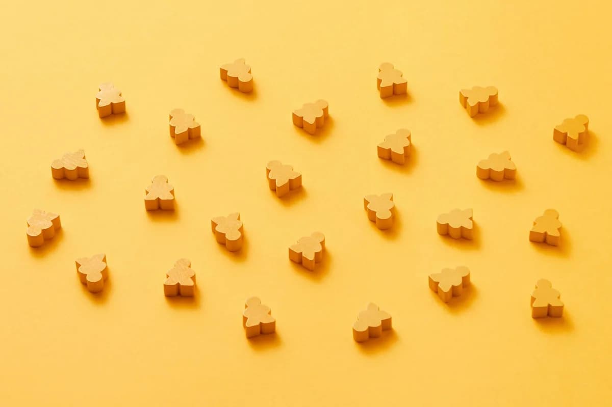 A minimalist arrangement of yellow meeple figures on a vibrant monochrome yellow background.