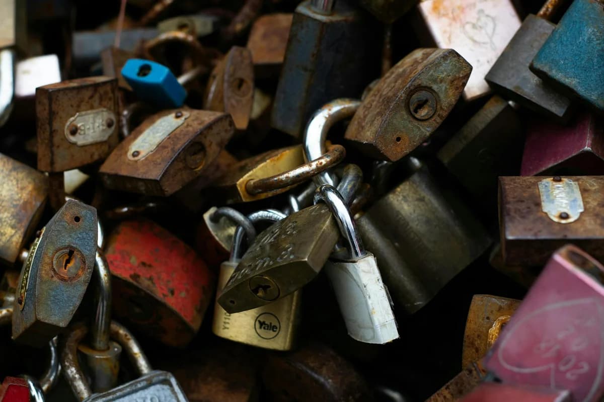 A brass padlock securing a rusty wire on a concrete post, symbolizing security and protection.