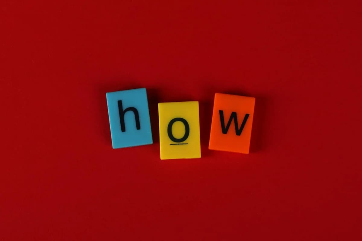 Colorful letter tiles spelling 'How' on a vibrant red background, ideal for educational content.