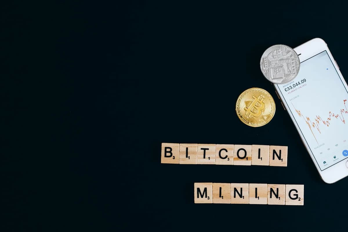 A collection of cryptocurrency coins and a smartphone displaying a digital trading platform.