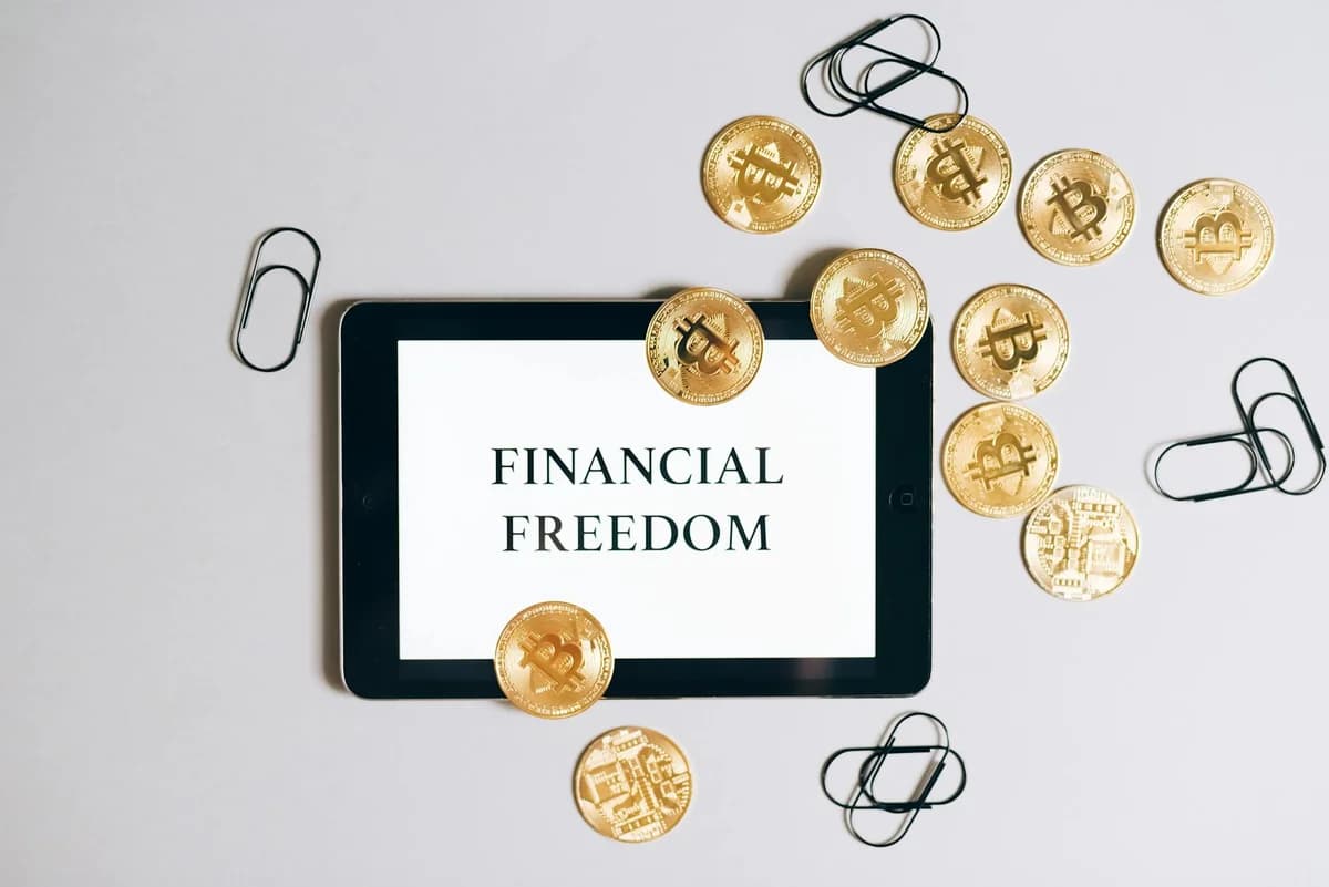 Top view of a tablet displaying 'Financial Freedom' with scattered bitcoin coins, symbolizing digital currency.