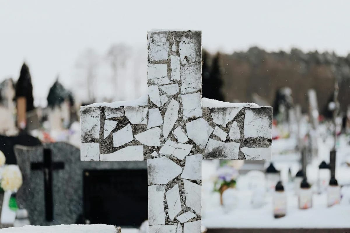 Golden Cross & Death Cross Explained for Crypto Beginners A mosaic cross stands in a snowy cemetery, capturing winter's tranquility and solitude.