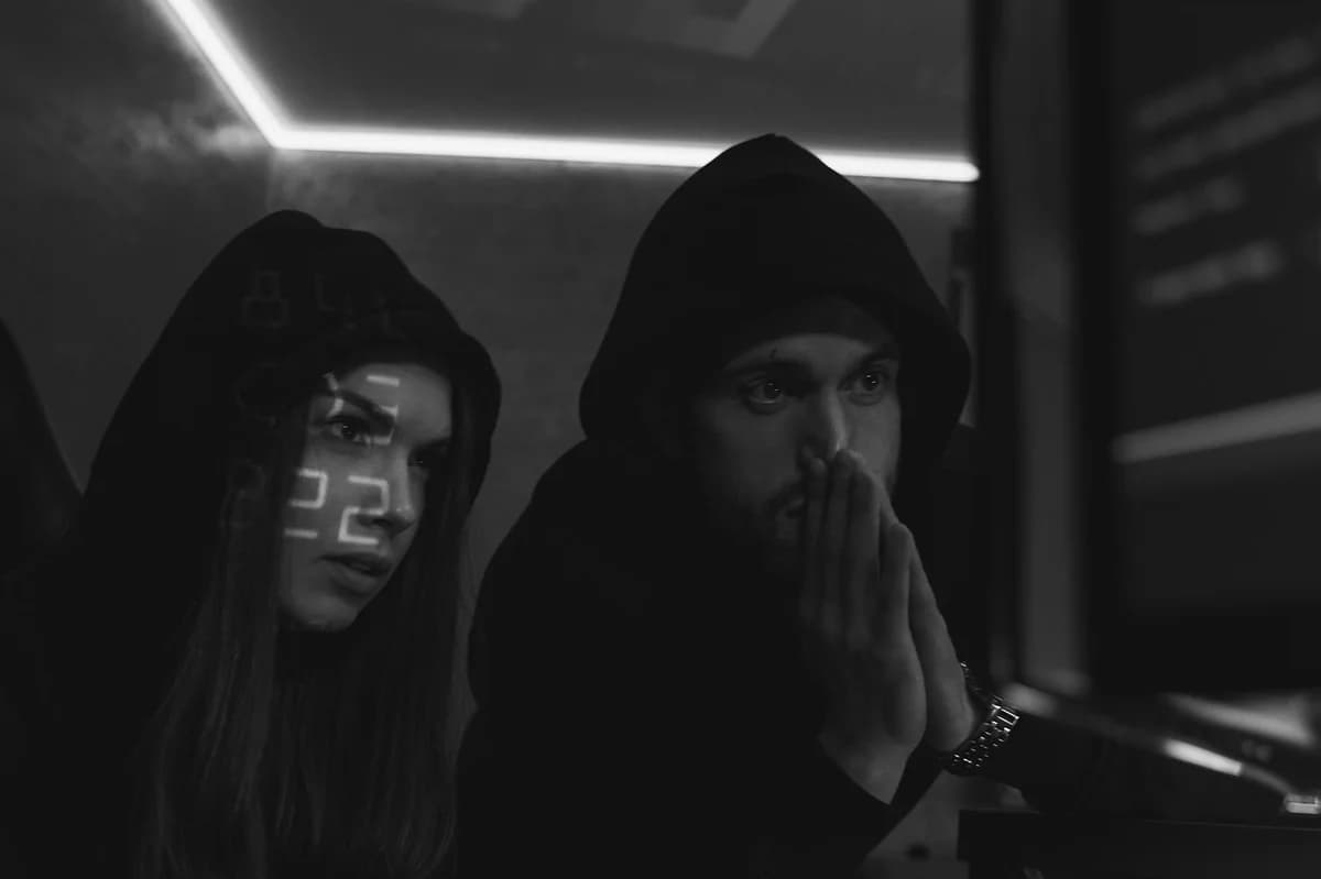 What Is the Biggest DeFi Hack of All Time? Two cybersecurity experts in hoodies study data on screens in a dimly lit room, symbolizing cyber defense.