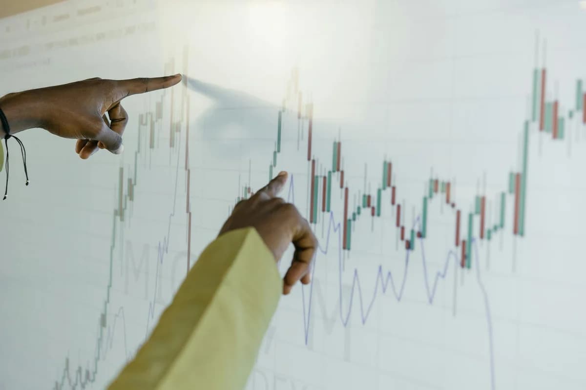 What Is the Reserve Risk Indicator? A Beginner's Guide Hands pointing at a financial stock chart on a digital screen, highlighting data analysis and trends.